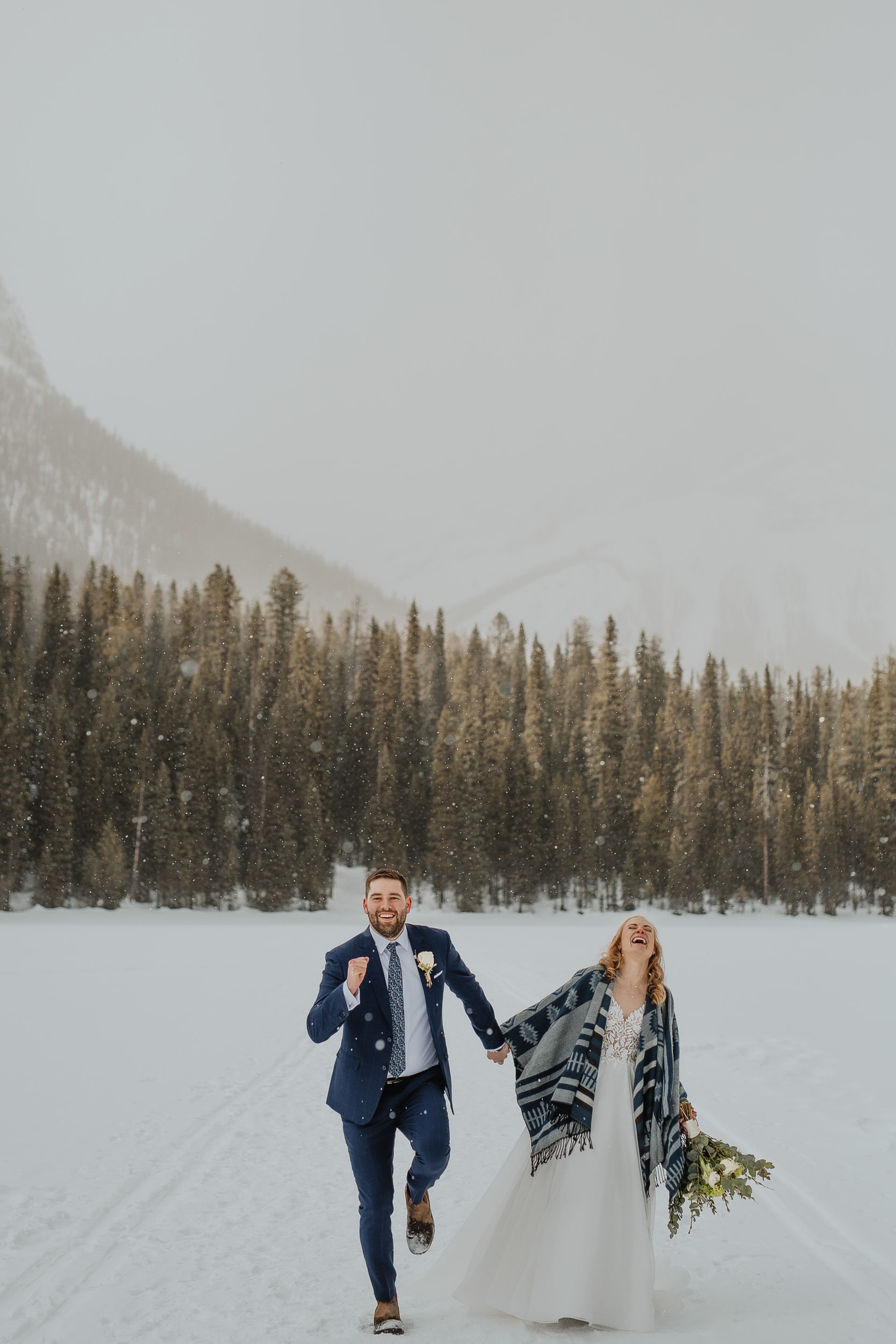 wedding couple walking in snow in the mountains